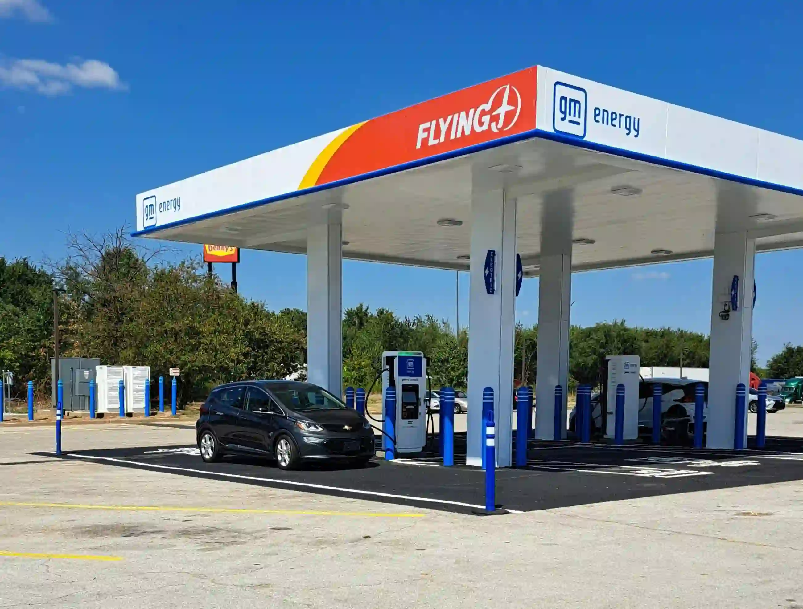 Coche eléctrico cargando en estación de servicio durante un viaje